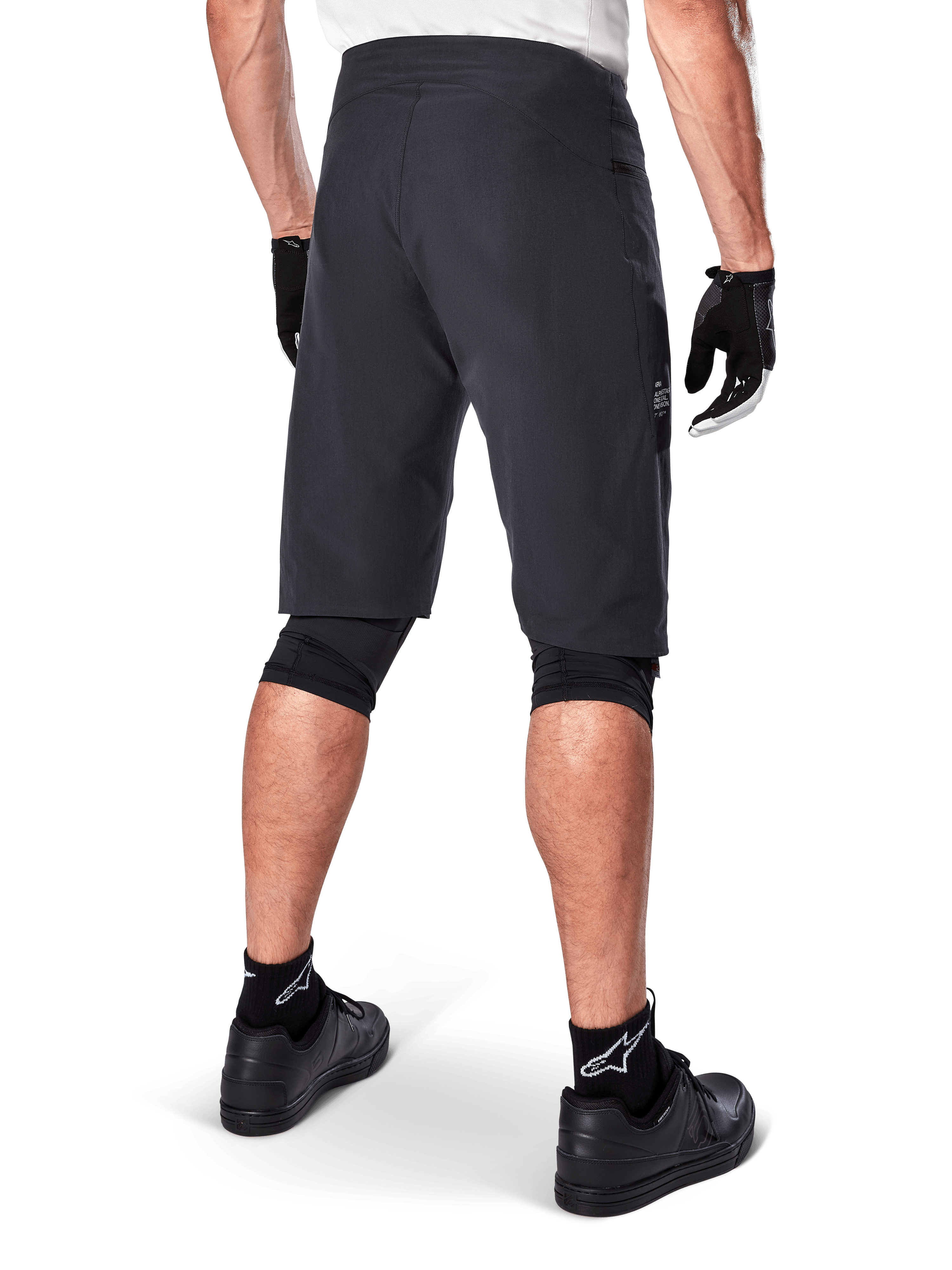 Short Alpinestars A-Aria, short de VTT, noir, vue arrière montrant la coupe performance et le design épuré, porté avec des gants noirs et des chaussettes arborant le logo blanc Astars, équipement de cyclisme technique pour le tout-terrain