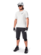 Vététiste homme portant le short Alpinestars A-Aria, short de cyclisme noir, associé à un maillot blanc à manches courtes, un casque de VTT blanc et un équipement technique noir, tenue complète pour la pratique du VTT tout-terrain