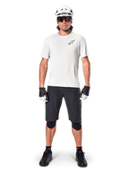 Vététiste homme portant le short Alpinestars A-Aria Noir, associé à un maillot technique blanc, un casque blanc et des protège-genoux noirs, équipement de cyclisme tout-terrain professionnel, vue de face complète