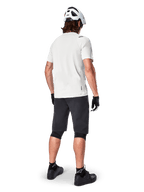 Vététiste de dos portant le short Alpinestars A-Aria noir, maillot de performance blanc à manches courtes, casque blanc, gants noirs et chaussures de VTT noires, équipement de cyclisme pour le trail
