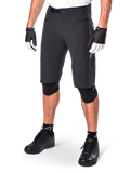 Alpinestars A-Aria Shorts, short de VTT noir, longueur genou avec poches avant zippées et boucle de taille à cliquet réglable, porté avec des genouillères noires, des chaussettes et des gants de cyclisme