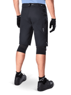 Shorts Alpinestars A-Dura Elite, Noir, vue arrière d'un cycliste portant un équipement de VTT comprenant des genouillères, des gants et des chaussettes noirs avec des logos blancs, doté de poches latérales zippées et d'accents réfléchissants sur un tissu Cordura durable.
