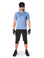 Short Alpinestars A-Dura Elite, short de VTT noir, porté avec un t-shirt bleu clair, un casque noir, des lunettes de soleil et des genouillères, tenue de cyclisme tout-terrain professionnelle