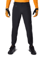 Alpinestars A-Dura broek, mountainbikebroek, zwart, gedragen met een oranje jersey met lange mouwen en zwart-oranje handschoenen, met een dubbele drukknoopsluiting en verstelbare tailleband aan de zijkant, duurzaam textiel voor mountainbiken