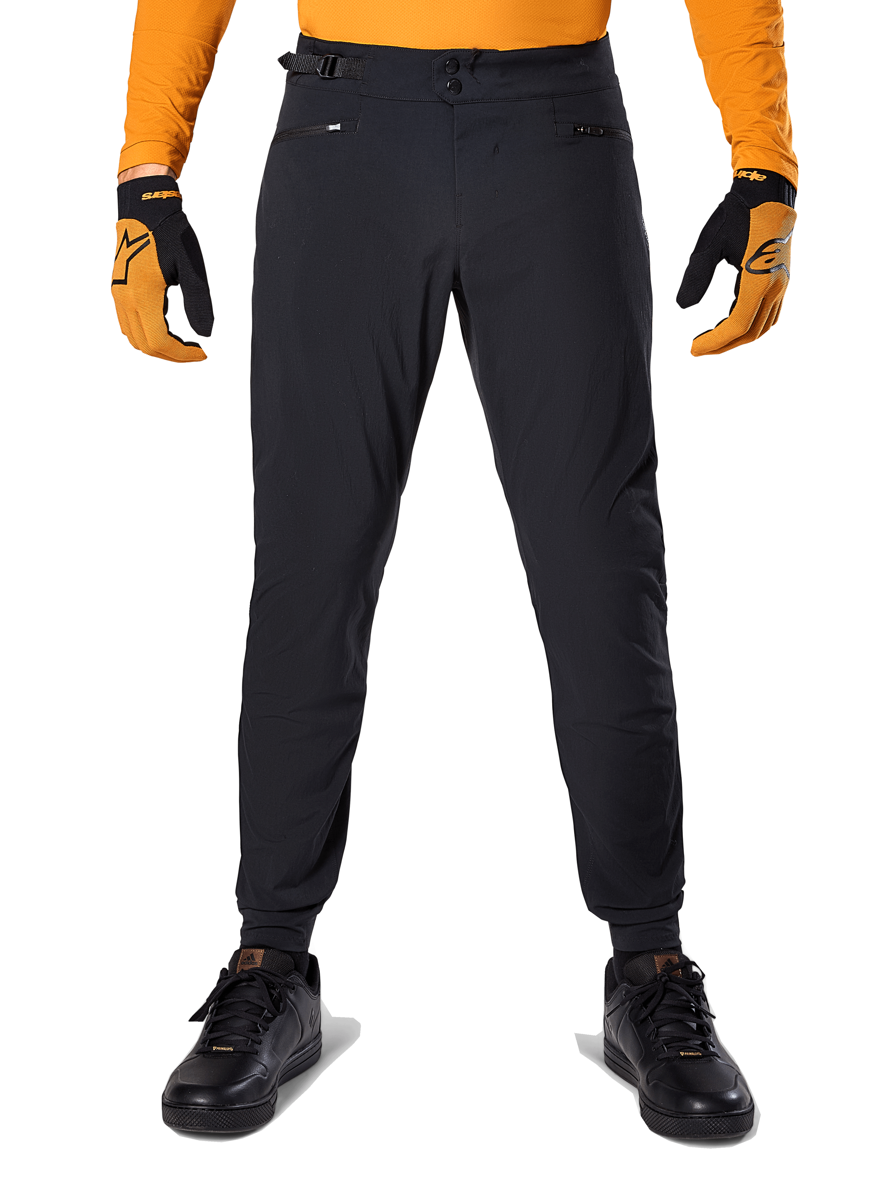 Alpinestars A-Dura broek, mountainbikebroek, zwart, gedragen met een oranje jersey met lange mouwen en zwart-oranje handschoenen, met een dubbele drukknoopsluiting en verstelbare tailleband aan de zijkant, duurzaam textiel voor mountainbiken