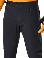 Alpinestars A-Dura Pants, zwarte MTB-broek, close-up met dubbele drukknoopsluiting, verstelbare tailleband aan de zijkant en zakken met rits, gecombineerd met een oranje jersey en handschoenen