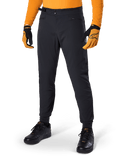 Alpinestars A-Dura Pants, mountainbikebroek, zwart, met zijsluitingen en zakken met rits, gedragen met oranje jersey en handschoenen, sportieve regular fit voor mountainbiken