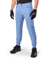 Alpinestars A-Dura broek, Infinity Blue MTB-fietsbroek, voorzien van een dubbele drukknoopsluiting en zakken met ritssluiting, gedragen met zwarte handschoenen en zwarte schoenen, duurzaam 2-way stretch textiel voor off-road ritten