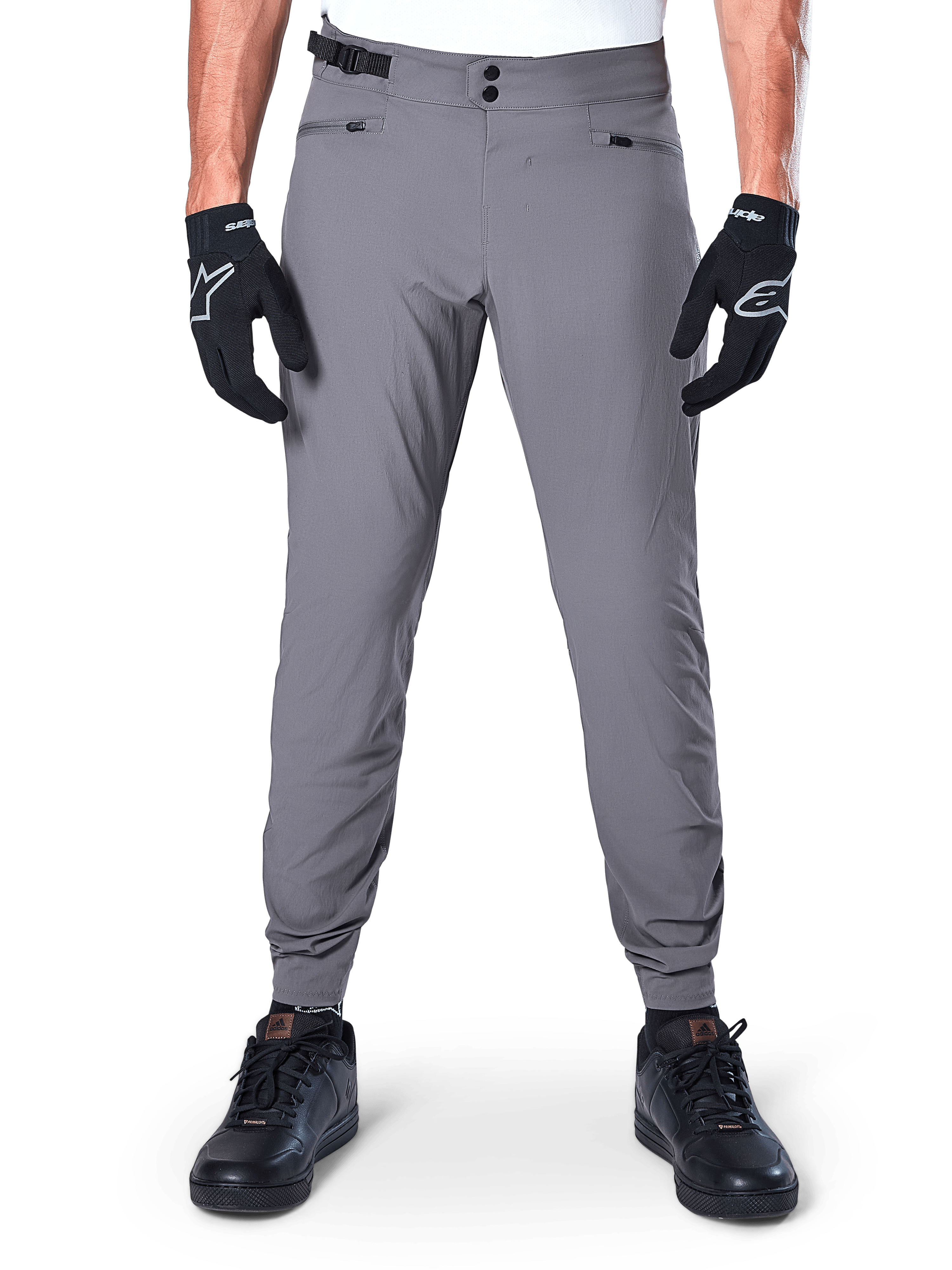 Alpinestars A-Dura Hose, dunkelgraue Mountainbike-Hose, Vorderansicht getragen mit schwarzen Handschuhen und schwarzen Sneakern, mit doppeltem Druckknopfverschluss, Reißverschlusstaschen und elastischen Bündchen, strapazierfähige Fahrradbekleidung für Trail-Riding