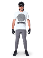 Alpinestars A-Dura Hose, MTB-Hose, Dunkelgrau, getragen mit einem weißen Grafik-T-Shirt, schwarzem Helm und Handschuhen, strapazierfähiges 2-Wege-Stretch-Design und reguläre Passform für Mountainbiking