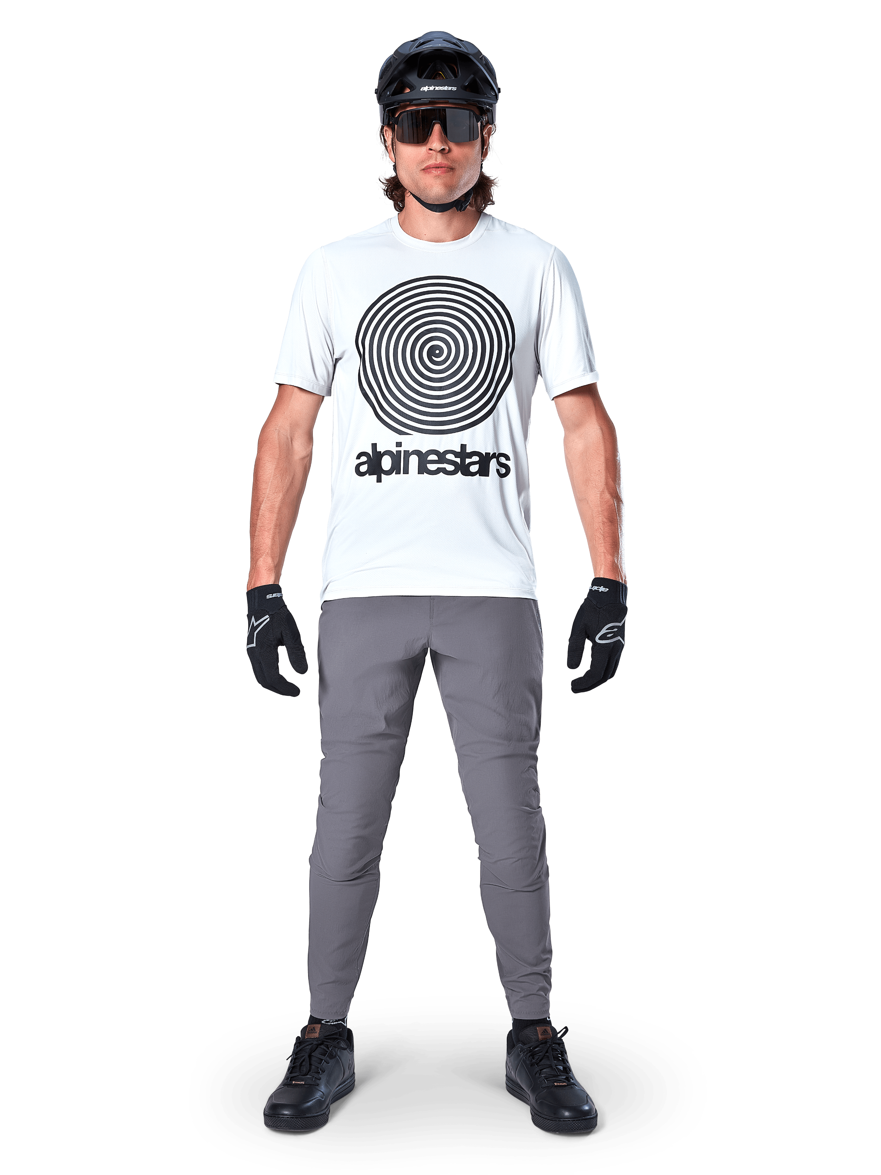 Alpinestars A-Dura Hose, MTB-Hose, Dunkelgrau, getragen mit einem weißen Grafik-T-Shirt, schwarzem Helm und Handschuhen, strapazierfähiges 2-Wege-Stretch-Design und reguläre Passform für Mountainbiking