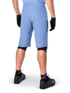 Short Alpinestars A-Dura, short de VTT bleu Infinity, vue de dos, associé à des gants noirs, des protections de genoux et des chaussettes noires avec logo étoile blanc, matériau extensible durable pour le cyclisme tout-terrain