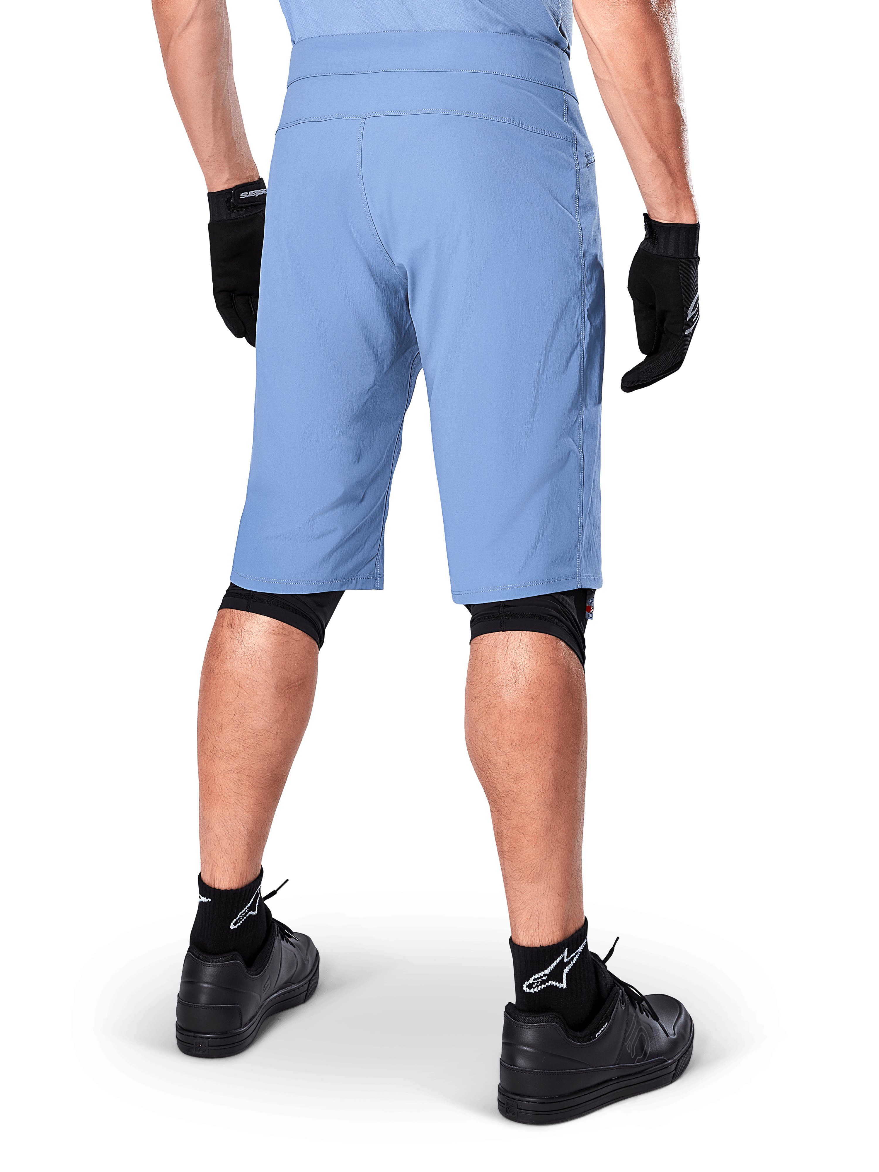 Short Alpinestars A-Dura, short de VTT bleu Infinity, vue de dos, associé à des gants noirs, des protections de genoux et des chaussettes noires avec logo étoile blanc, matériau extensible durable pour le cyclisme tout-terrain