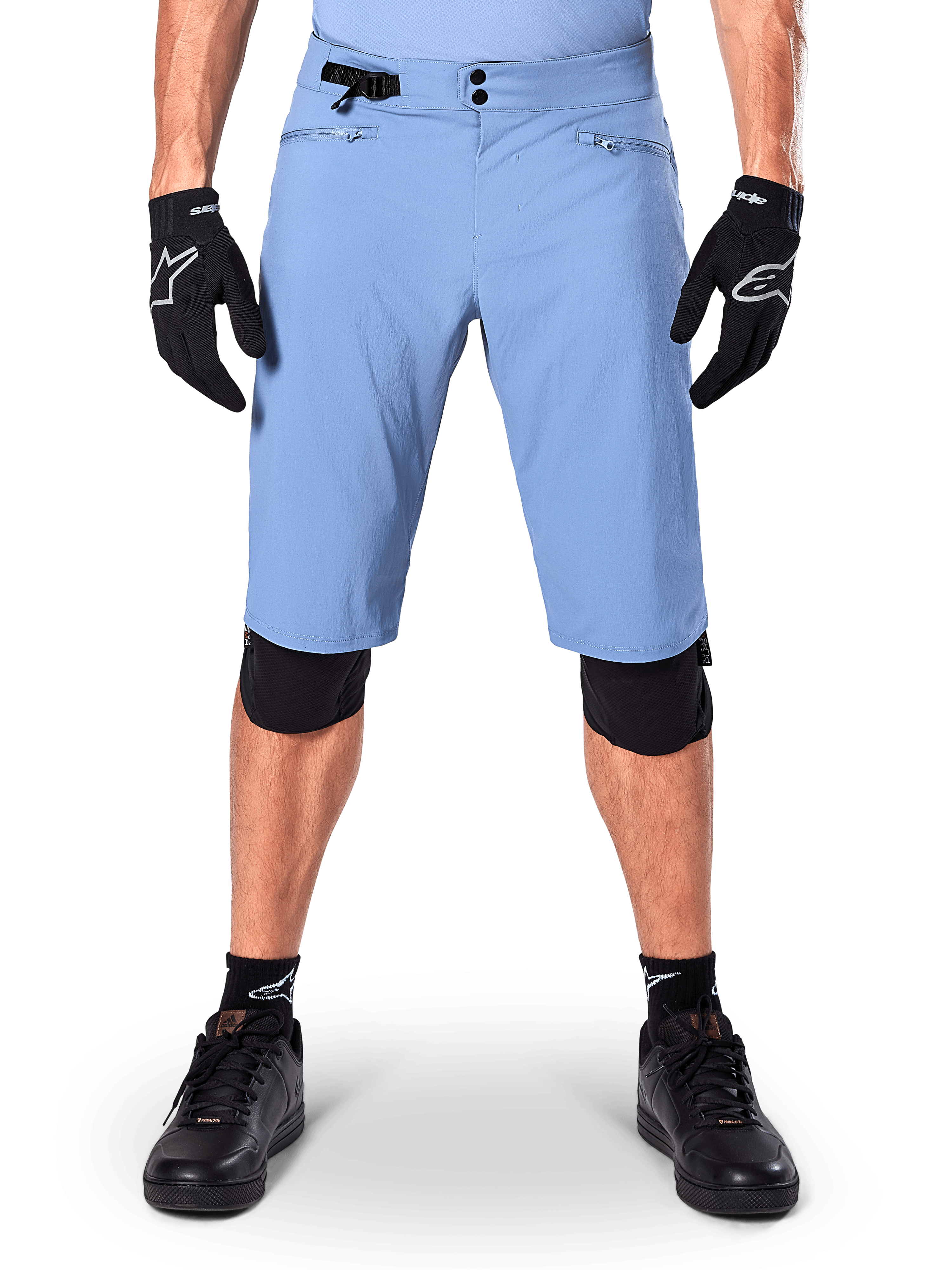 Short Alpinestars A-Dura, short de VTT bleu Infinity Blue, porté avec des gants noirs et des genouillères, doté d'une double fermeture à pression et d'un ajusteur de taille latéral, équipement de cyclisme haute performance pour le VTT