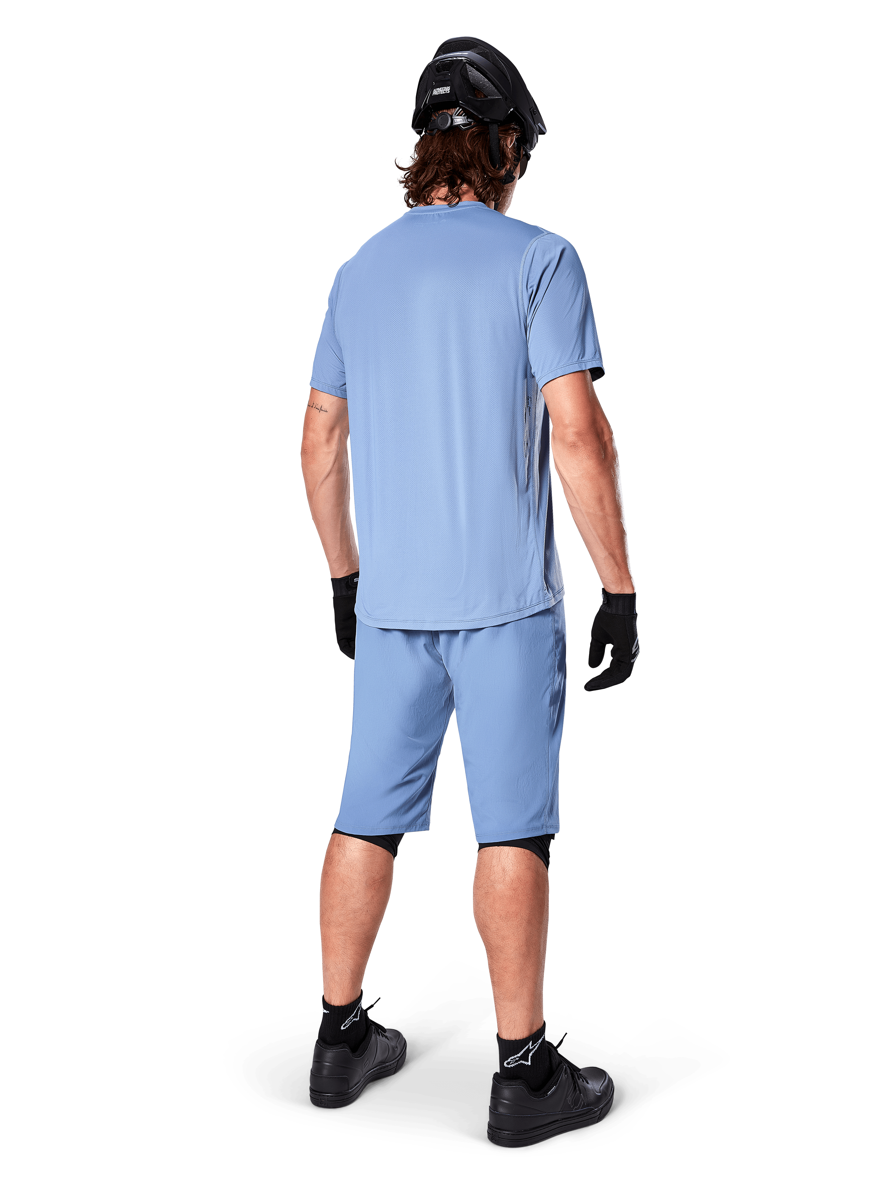 Vue arrière d'un vététiste portant le short Alpinestars A-Dura en Infinity Blue, maillot à manches courtes assorti, casque noir, gants noirs et chaussures noires, équipement de performance coordonné pour le trail VTT