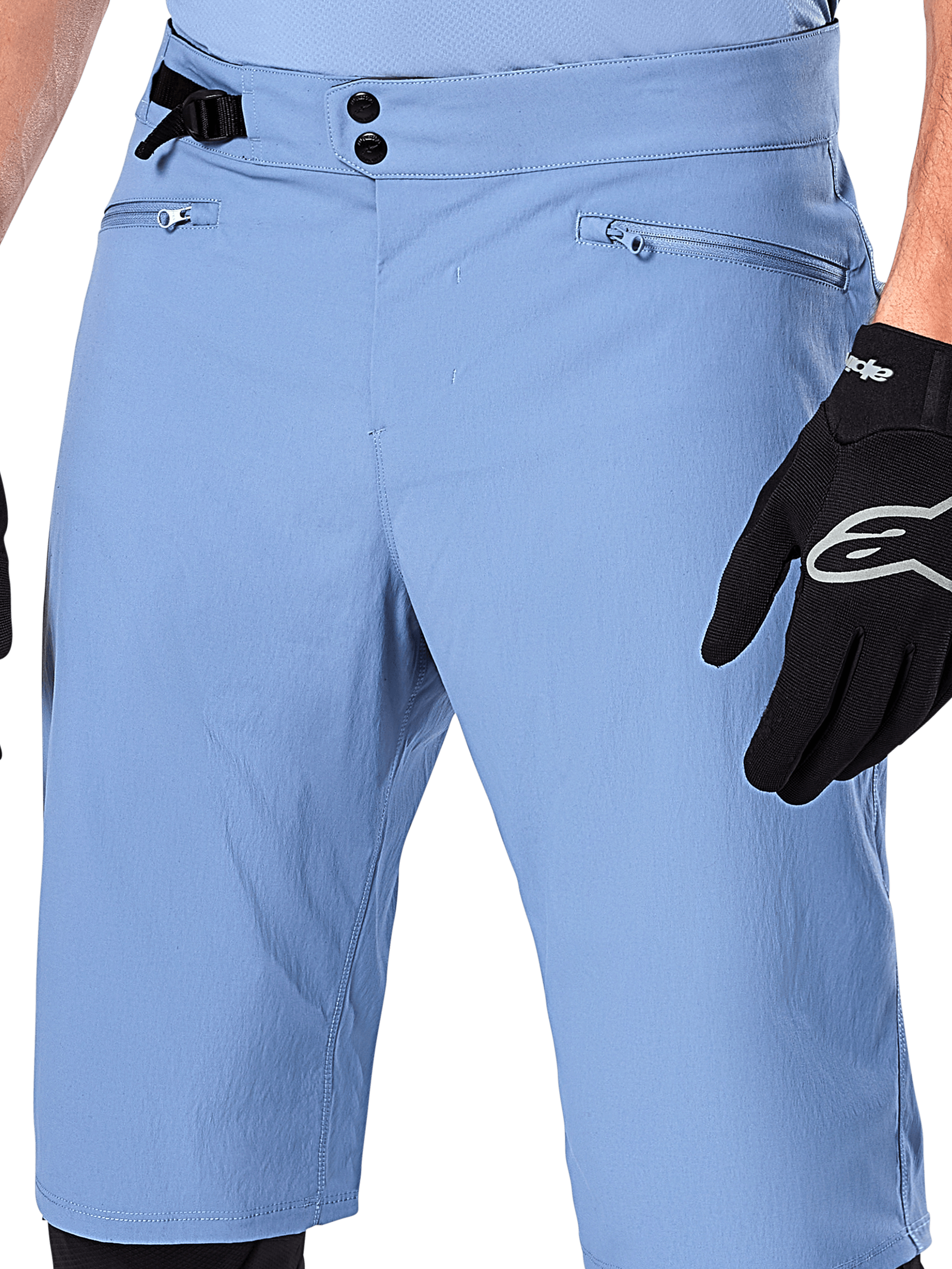Short Alpinestars A-Dura, short de VTT bleu Infinity, gros plan sur la taille doté d'une double fermeture à pression, d'un ajusteur latéral et de poches zippées doublées en maille, porté avec un gant Alpinestars noir
