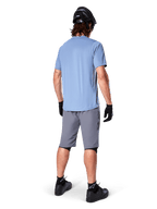 Alpinestars A-Dura Shorts, short de VTT gris foncé, vue de dos, porté avec un maillot bleu clair à manches courtes et un casque de VTT noir, gants et chaussettes noirs avec chaussures noires, équipement fonctionnel et durable pour le cyclisme tout-terrain