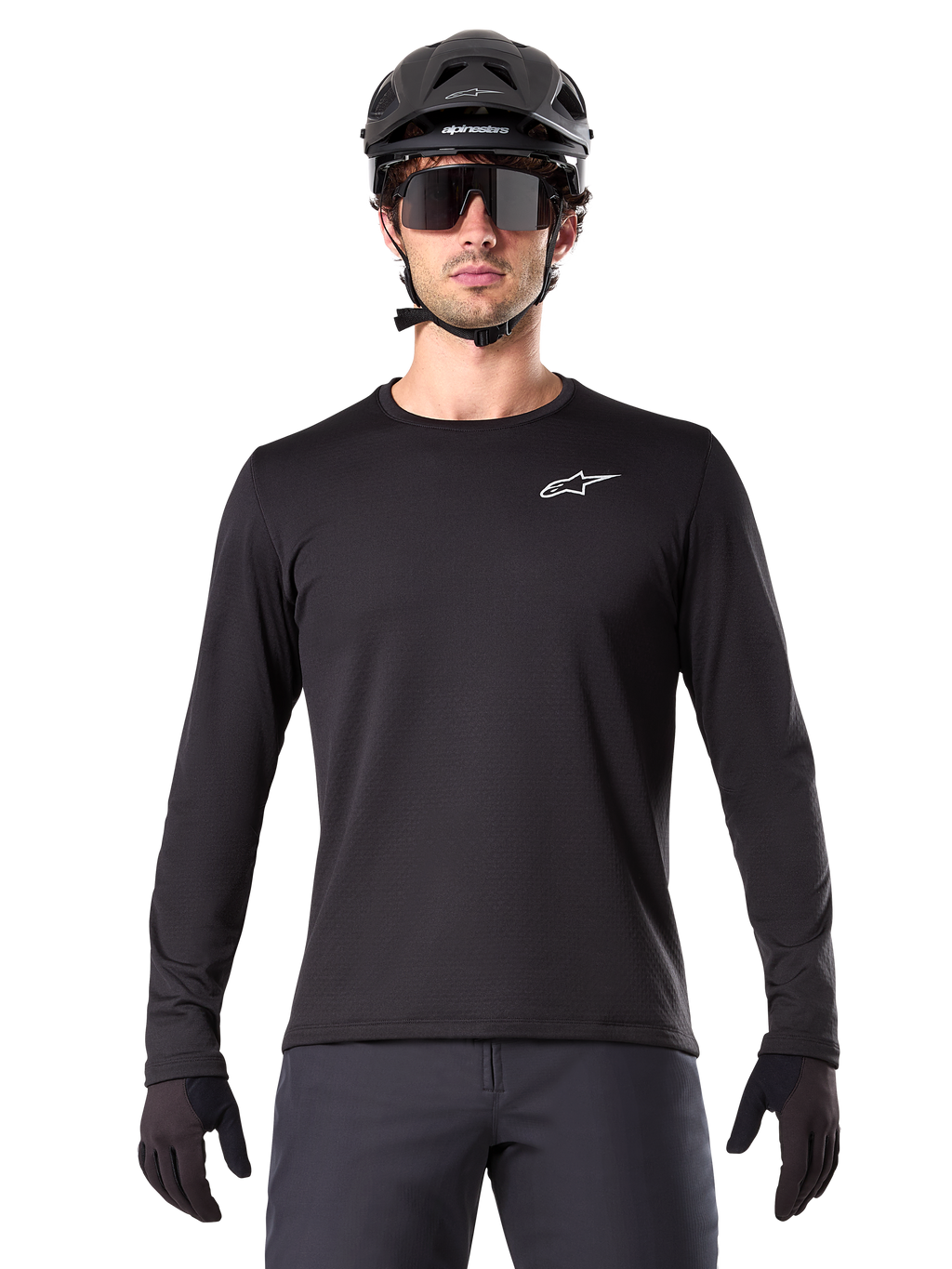 Maillot thermique Alpinestars A-Dura, maillot de VTT à manches longues noir, porté avec un casque noir et de larges lunettes de soleil, petit logo Alpinestars blanc sur la poitrine, coupe classique, équipement de cyclisme VTT