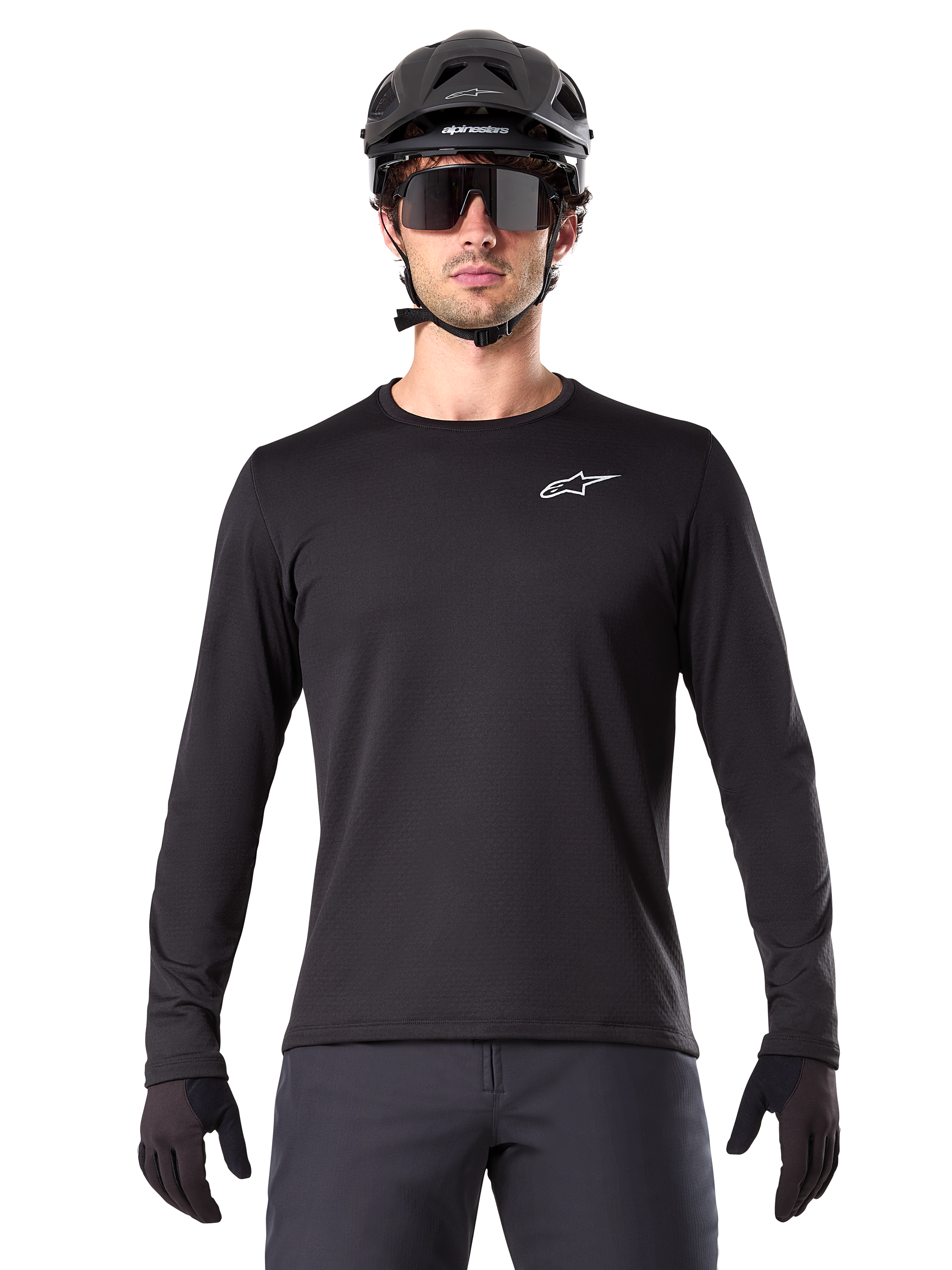 Maillot thermique Alpinestars A-Dura, maillot de VTT à manches longues noir, porté avec un casque noir et de larges lunettes de soleil, petit logo Alpinestars blanc sur la poitrine, coupe classique, équipement de cyclisme VTT