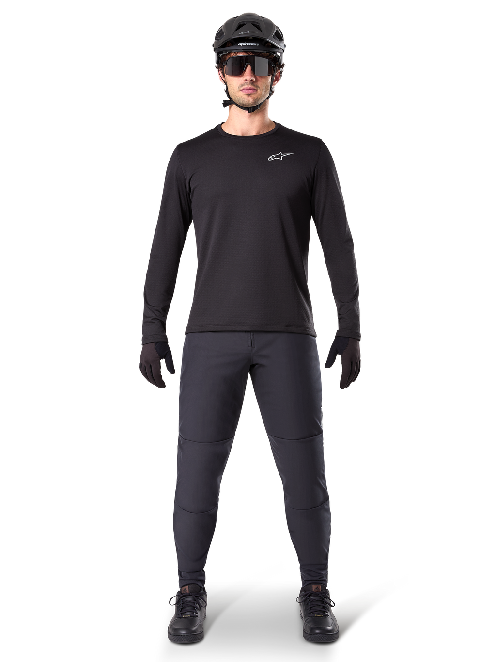 Alpinestars A-Dura Thermal Jersey, maillot de VTT à manches longues noir, porté avec un pantalon gris foncé, des gants noirs, un casque noir et des lunettes de soleil, logo Alpinestars blanc sur la poitrine, tenue coordonnée pour le VTT par temps froid
