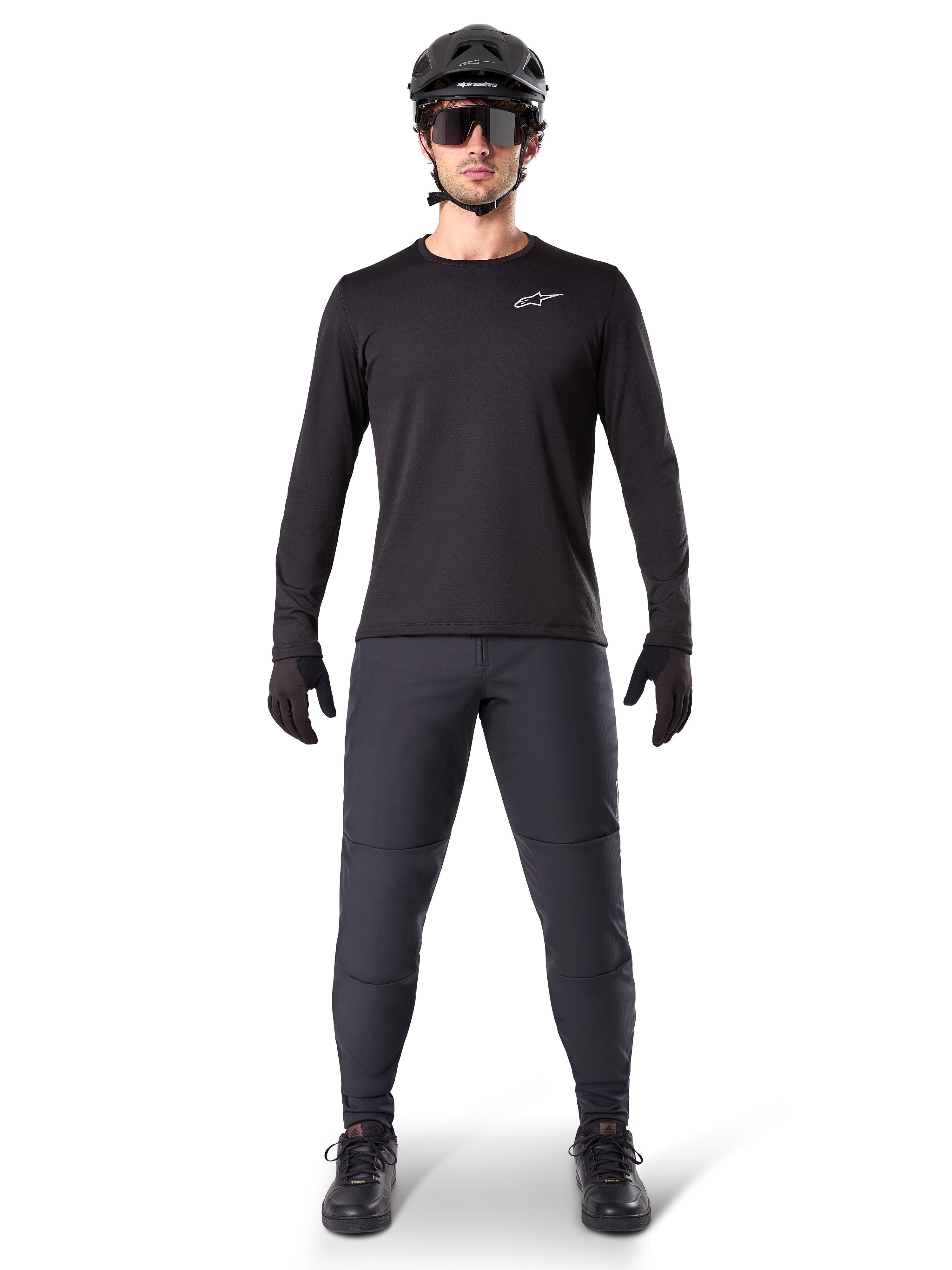 Alpinestars A-Dura Thermal Jersey, maillot de VTT à manches longues noir, porté avec un pantalon gris foncé, des gants noirs, un casque noir et des lunettes de soleil, logo Alpinestars blanc sur la poitrine, tenue coordonnée pour le VTT par temps froid