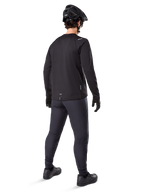 Maillot thermique Alpinestars A-Dura, maillot de cyclisme à manches longues pour homme, noir, vue arrière sur mannequin portant un casque de VTT noir, un pantalon gris foncé et des gants noirs, tenue de VTT professionnelle pour temps froid