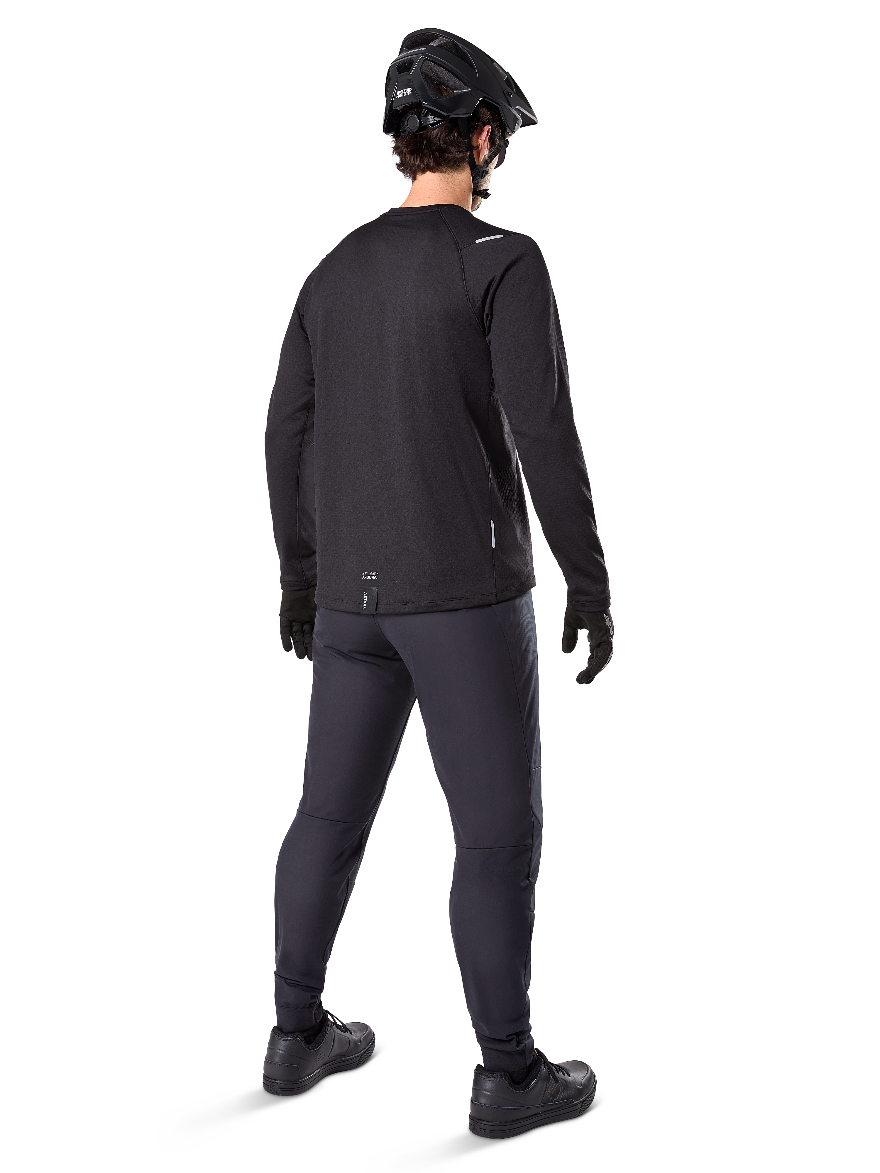 Maillot thermique Alpinestars A-Dura, maillot de cyclisme à manches longues pour homme, noir, vue arrière sur mannequin portant un casque de VTT noir, un pantalon gris foncé et des gants noirs, tenue de VTT professionnelle pour temps froid