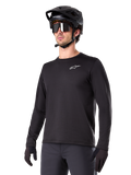 Alpinestars A-Dura Thermal Jersey, maillot de VTT à manches longues noir, logo blanc sur la poitrine, porté avec un casque et des gants noirs, design sportif et épuré pour le trail