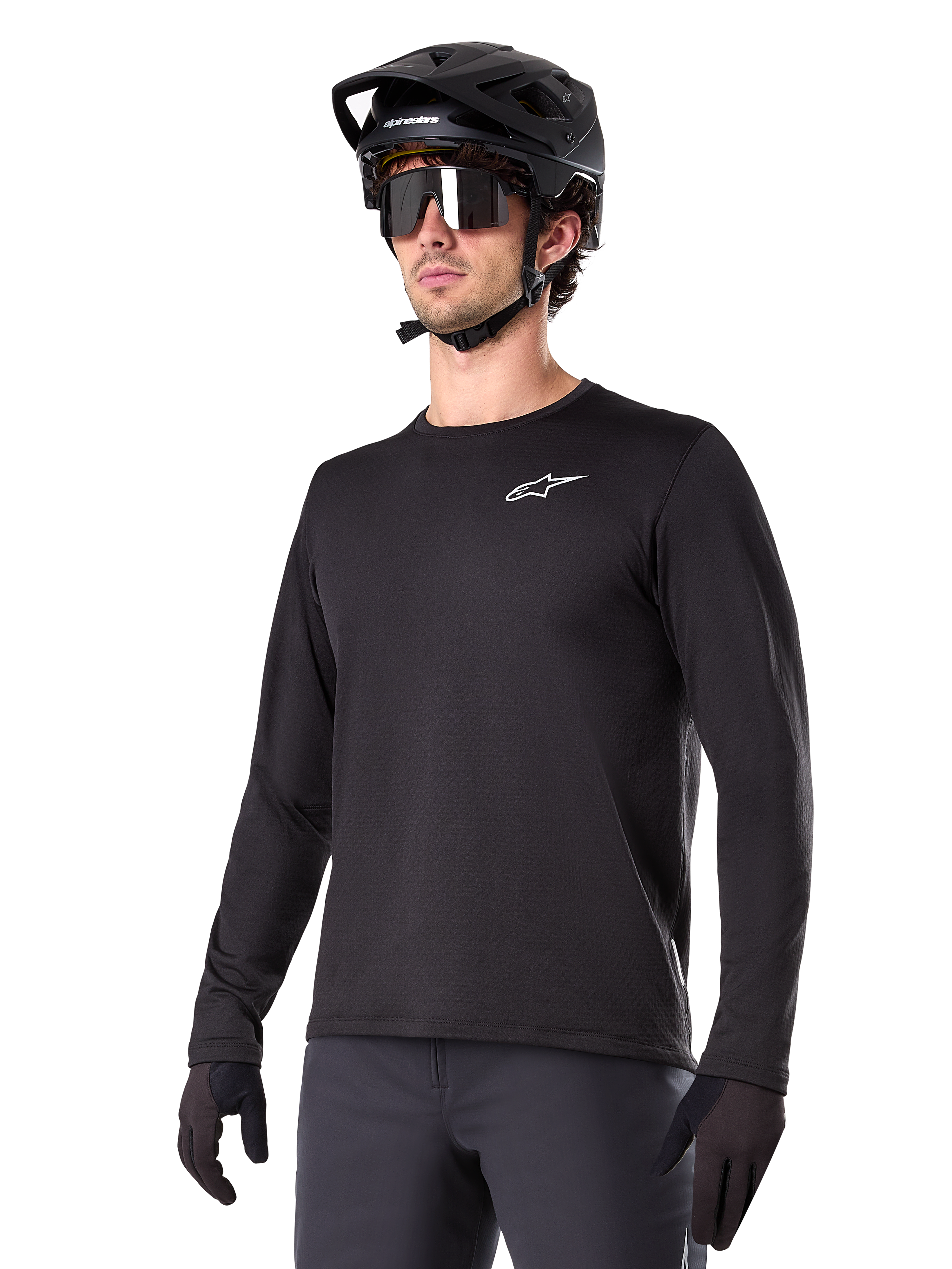 Alpinestars A-Dura Thermal Jersey, zwart mountainbikeshirt met lange mouwen, wit logo op de borst, gedragen met zwarte helm en handschoenen, strak sportief ontwerp voor trailrijden