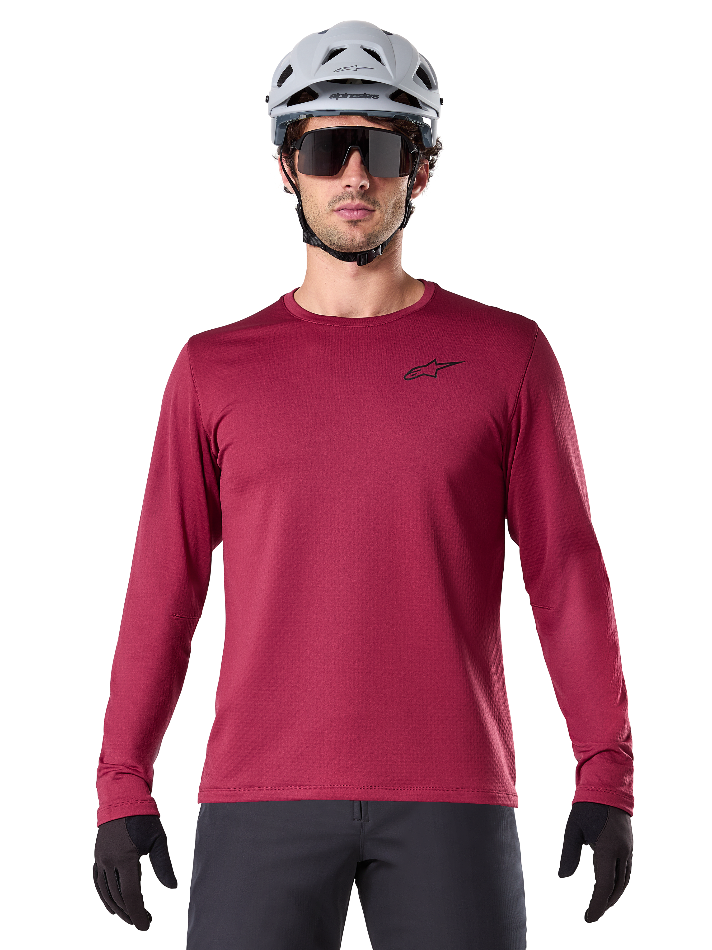 Maillot thermique Alpinestars A-Dura, maillot de VTT à manches longues pour homme, bordeaux, porté avec un casque gris et des lunettes de soleil noires, avec un petit logo étoile sur la poitrine, tissu polaire isolant pour le VTT par temps froid