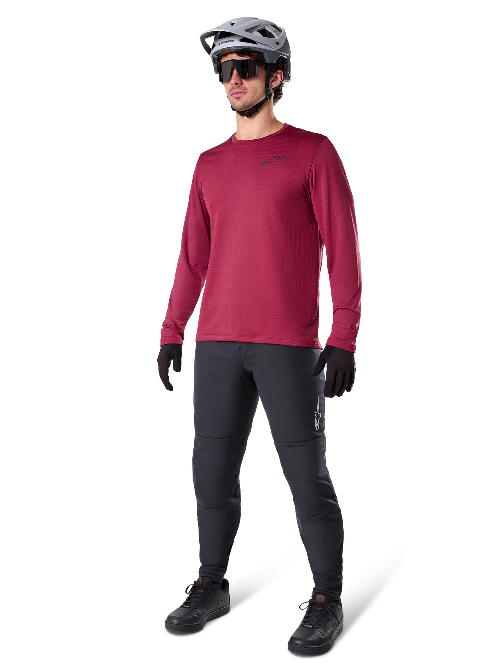 Maillot thermique Alpinestars A-Dura bordeaux, haut de cyclisme isolant à manches longues porté avec un pantalon de VTT gris foncé, des gants noirs et un casque gris, tenue complète de VTT pour temps froid, photo en studio