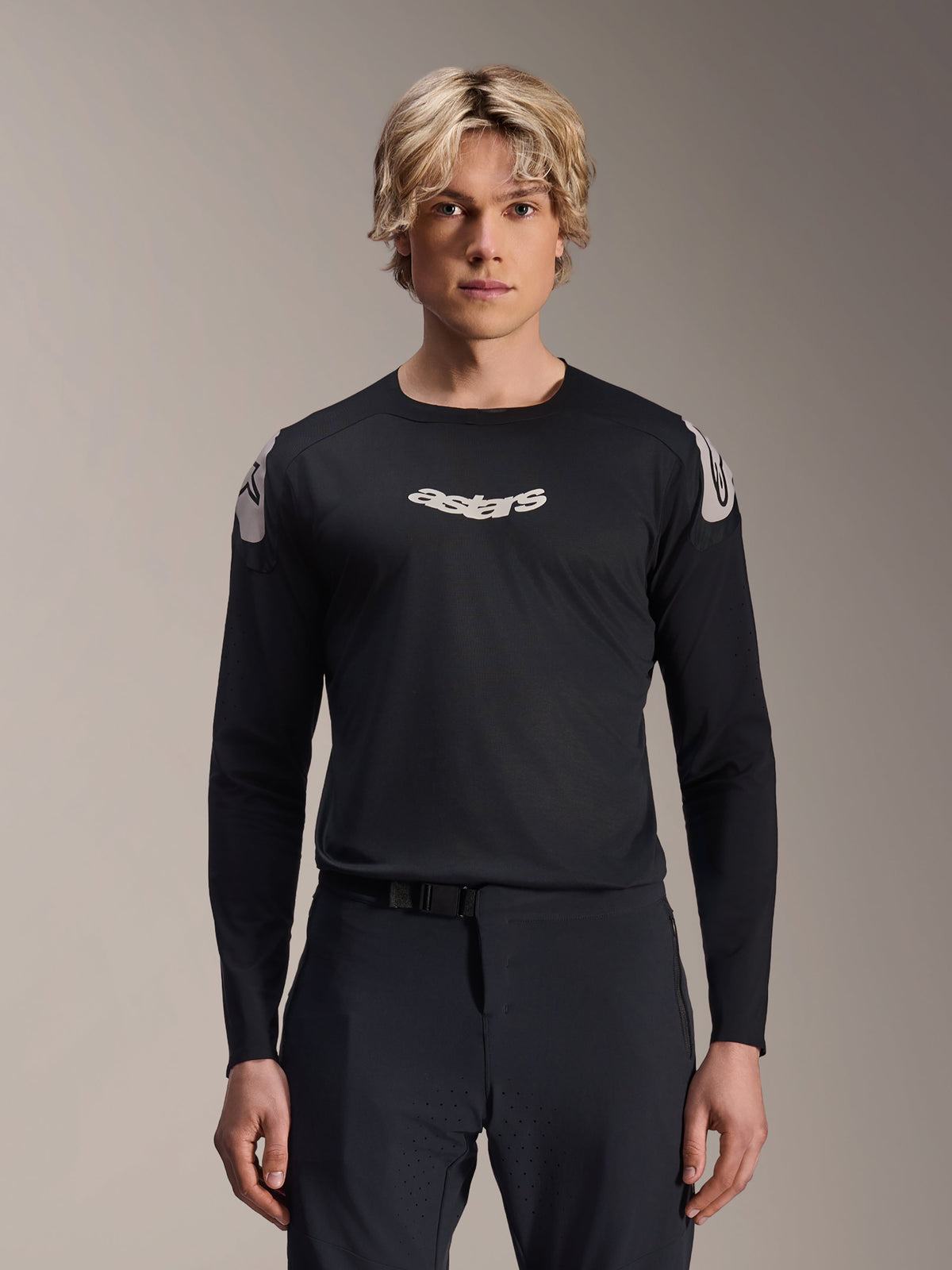 Alpinestars A-Aria Polartec Elite Trikot, Langarm-MTB-Trikot, Schwarz, mit weißem „astars“-Brustlogo und weißen Grafiken an den Schultern, Performance-Radsportausrüstung getragen von einem Modell