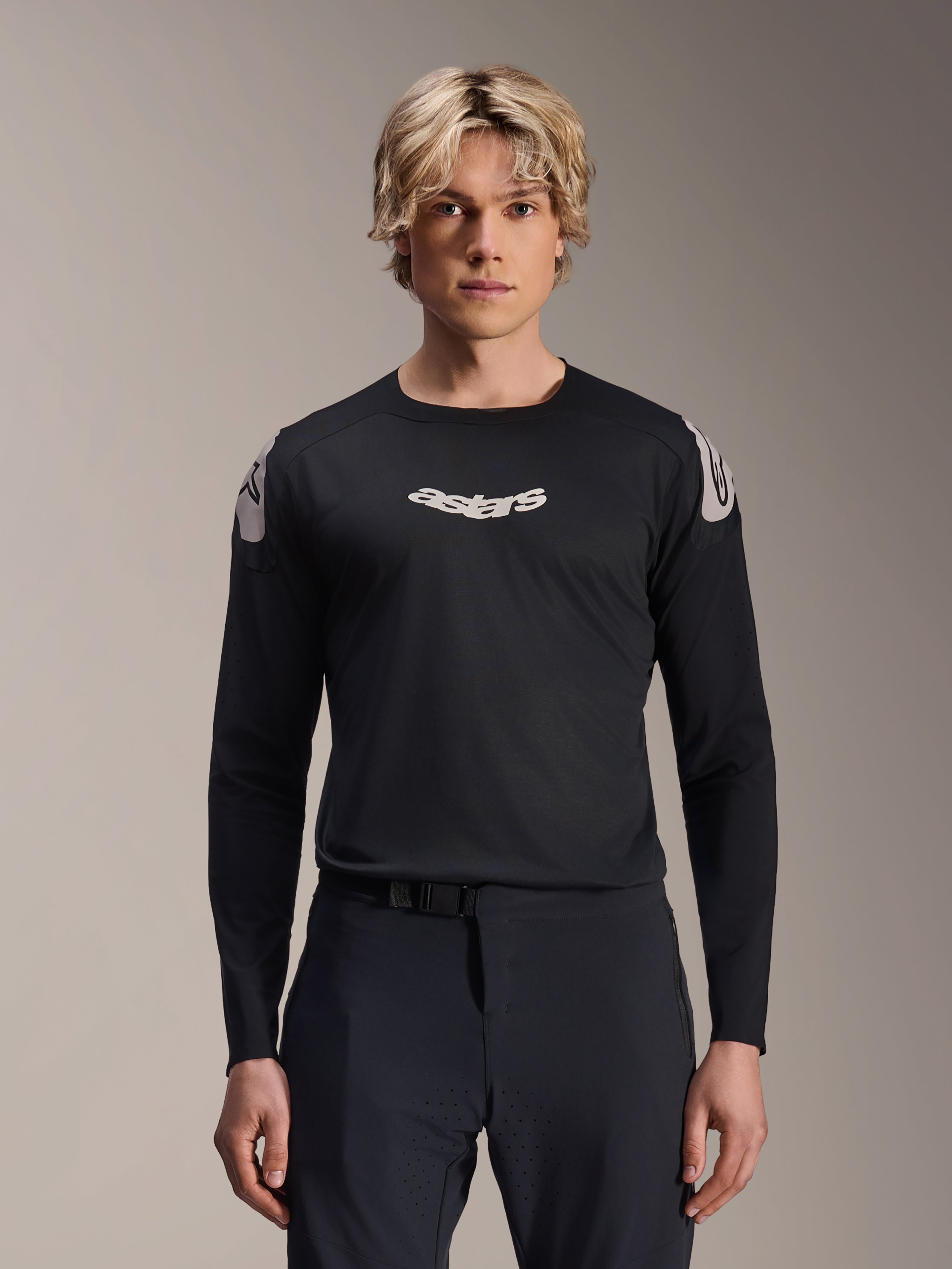 Alpinestars A-Aria Polartec Elite Trikot, Langarm-MTB-Trikot, Schwarz, mit weißem „astars“-Brustlogo und weißen Grafiken an den Schultern, Performance-Radsportausrüstung getragen von einem Modell