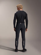 Alpinestars A-Aria Elite broek, Black Titanium, achteraanzicht op mannelijk model, met zilveren Alpinestars-branding op de onderbenen, technische MTB-broek met prestatiepasvorm en vochtafvoerend detail in de tailleband