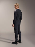 Alpinestars A-Aria Elite Pants, mountainbikebroek, Black Titanium, driekwart achteraanzicht op model, voorzien van witte Alpinestars-branding op de onderbenen, performance-pasvorm met elastische boorden, gecombineerd met een bijpassende zwarte jersey met lange mouwen.