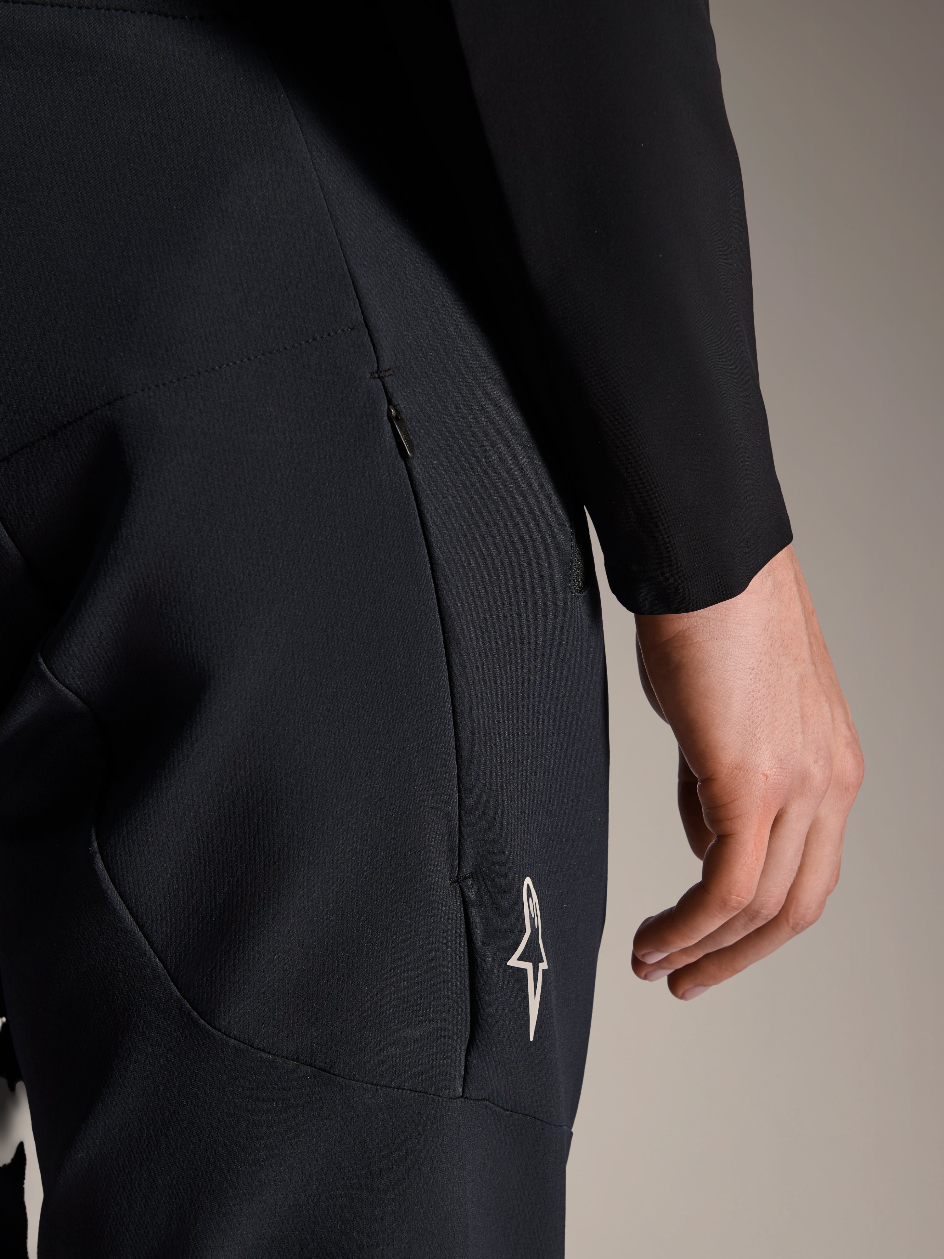Alpinestars A-Aria Elite broek in Black Titanium, detailopname van een zijzak met rits en een klein wit sterlogo, technische mountainbikebroek voor prestatiegericht fietsen