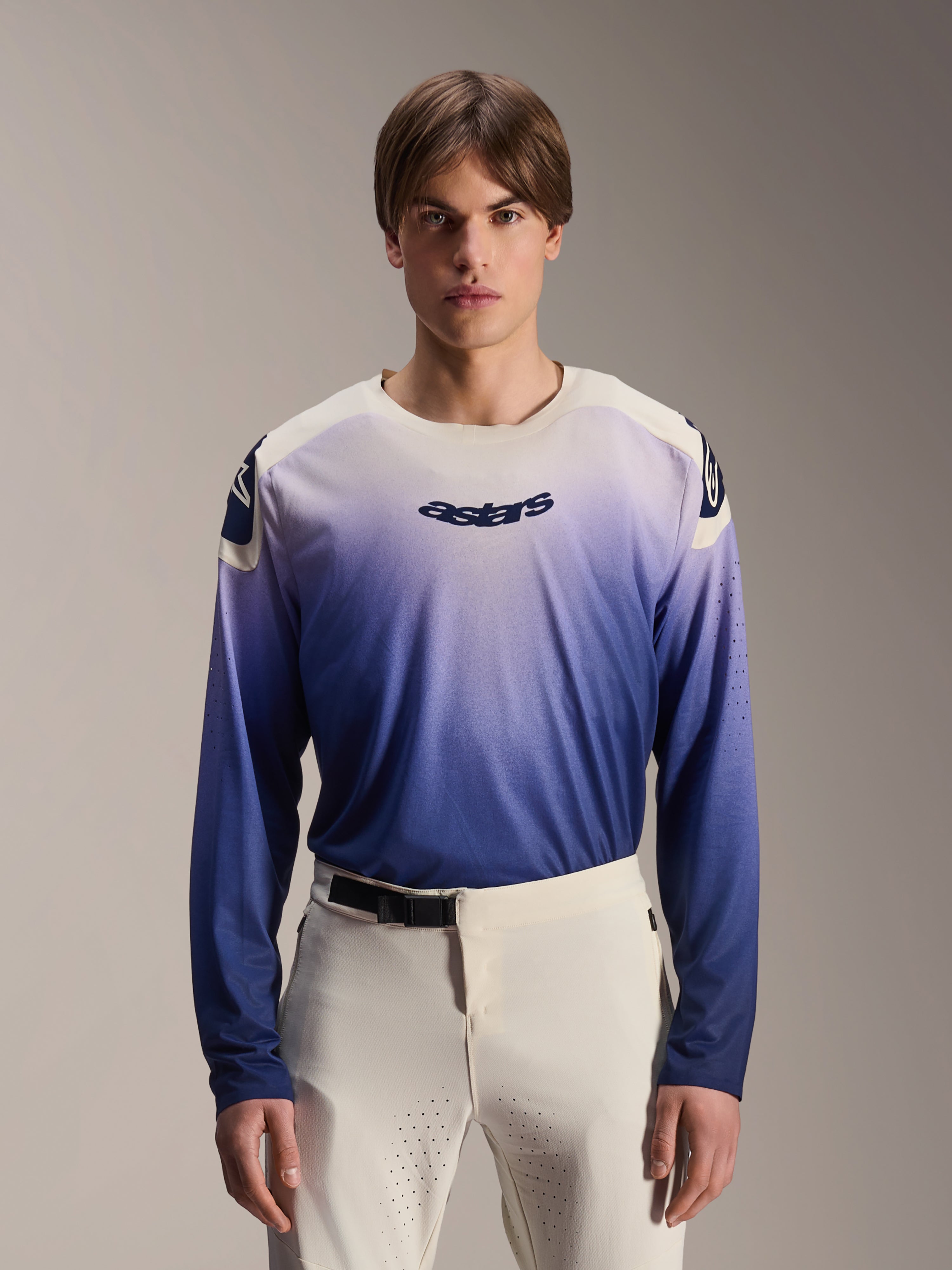 Maillot Alpinestars A-Aria Polartec Maker Elite, maillot de VTT à manches longues, bleu Baja avec dégradé du blanc vers le bleu, porté par un mannequin avec un pantalon blanc, logo bleu foncé sur la poitrine et perforations laser sur les manches, vêtement de performance pour le VTT