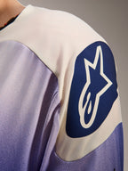 Maillot Alpinestars A-Aria Polartec Maker Elite, maillot de VTT à manches longues, bleu Baja et blanc, gros plan sur l'épaule avec logo Alpinestars circulaire bleu et étoile blanche, mettant en avant les perforations laser et la texture technique du tissu