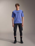 Alpinestars A-Aria Lite Short, heren mountainbike short, zwart, gedragen met lichtpaars shirt met korte mouwen en zwarte kniebeschermers, performance MTB-kleding