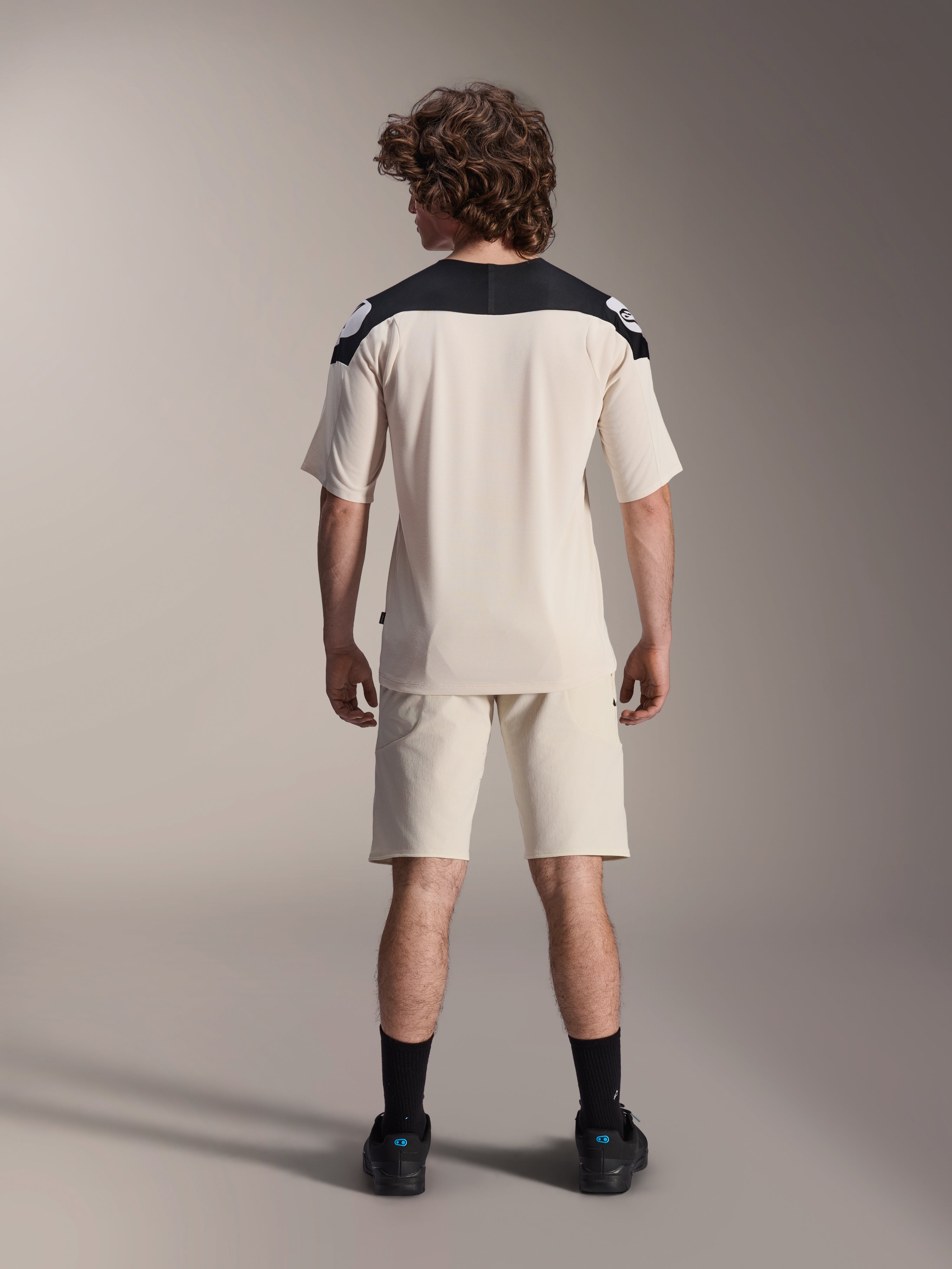Alpinestars A-Aria Elite Shorts und A-Aria Polartec Elite SS Jersey, Ecru mit schwarzen Schulterpartien, Rückansicht eines Models in Mountainbike-Performance-Ausrüstung, kombiniert mit schwarzen Socken und Schuhen