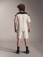 Alpinestars A-Aria Polartec Elite Kurzarmtrikot, MTB-Fahrradtrikot, Ecru mit schwarzen Schulterpartien, Rückansicht mit passenden Shorts und schwarzen Socken, Performance-Passform mit verlängertem Rückenteil für den Offroad-Einsatz.