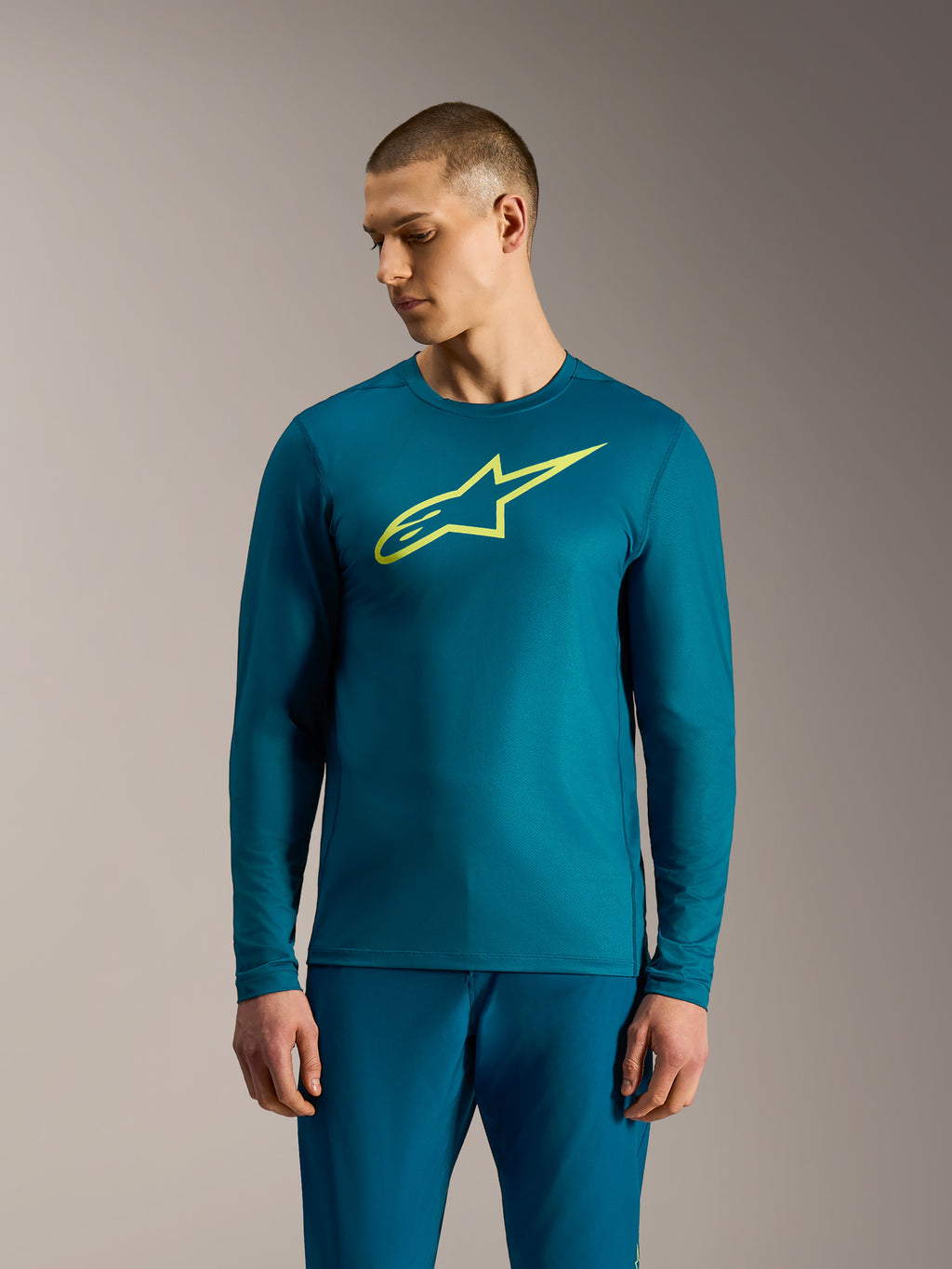 Blauwgroene A-Dura Ride trui met lange mouwen, limoengeel Alpinestars-logo, technische mountainbike-kleding.