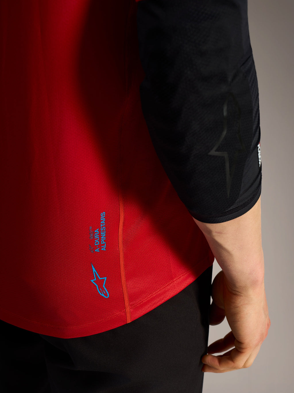 Détail du maillot A-Dura Ride Alpinestars rouge avec logos bleus, tissu technique performant pour le VTT.