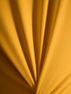 Close-up van de oranje A-Dura Ride Jersey textuur, lichtgewicht jacquard poly/spandex materiaal.