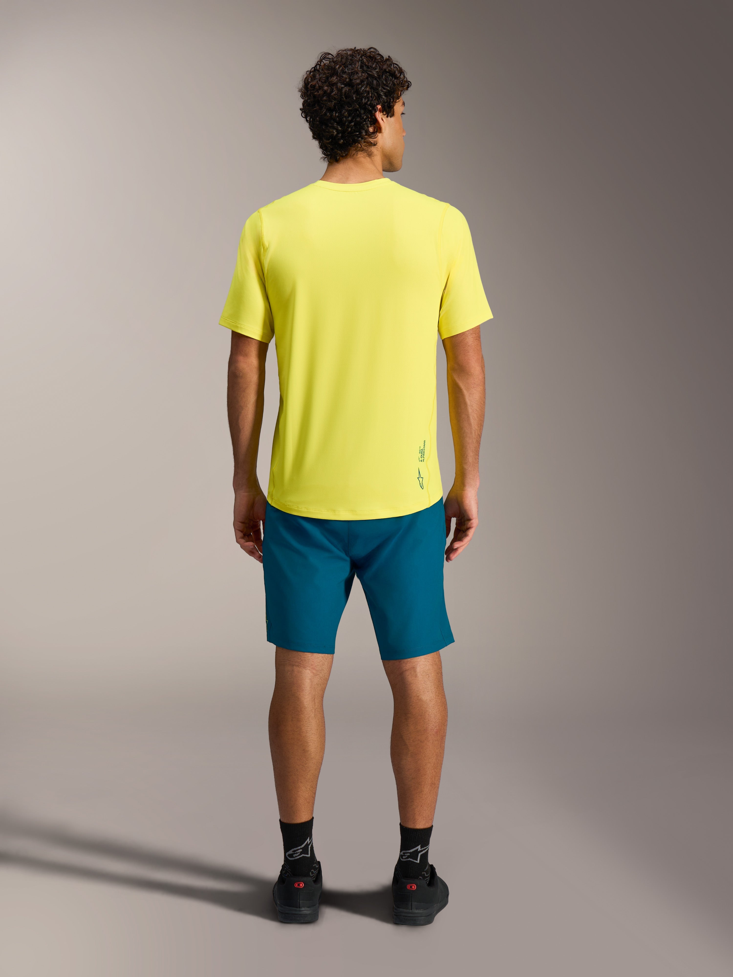 Maillot jaune A-Dura Ride SS et short bleu-vert A-Dura Ride vus de dos, équipement performant pour le VTT.