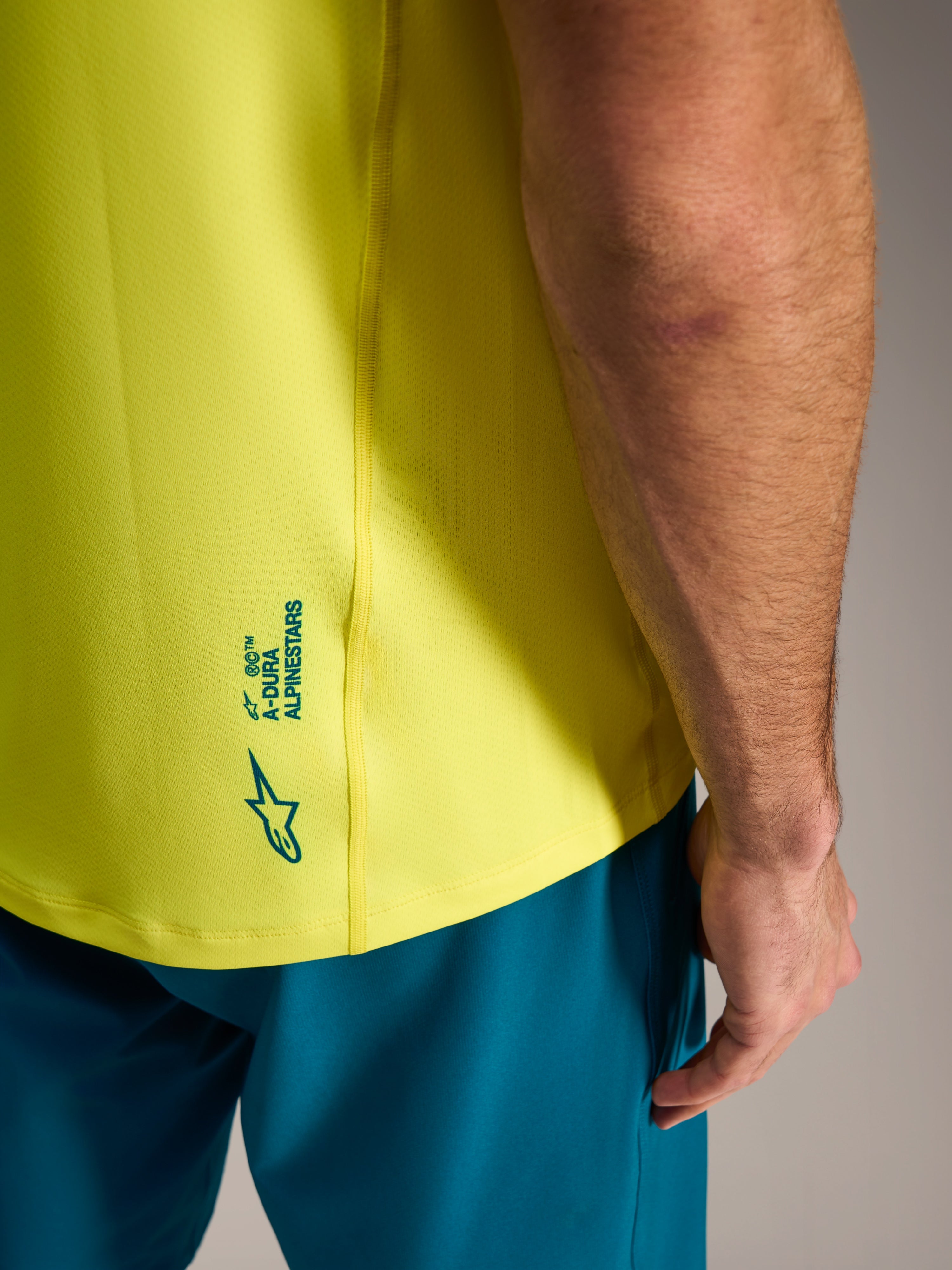 Maillot VTT A-Dura Ride jaune fluo avec logo Alpinestars au bas du dos, vêtement de cyclisme léger.