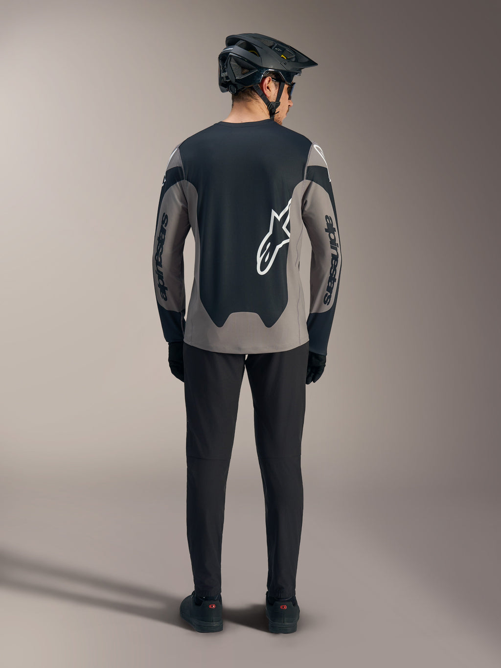 Grijze A-Dura Race MTB-jersey met lange mouwen, achteraanzicht met zwarte panelen en witte Alpinestars-logo's.