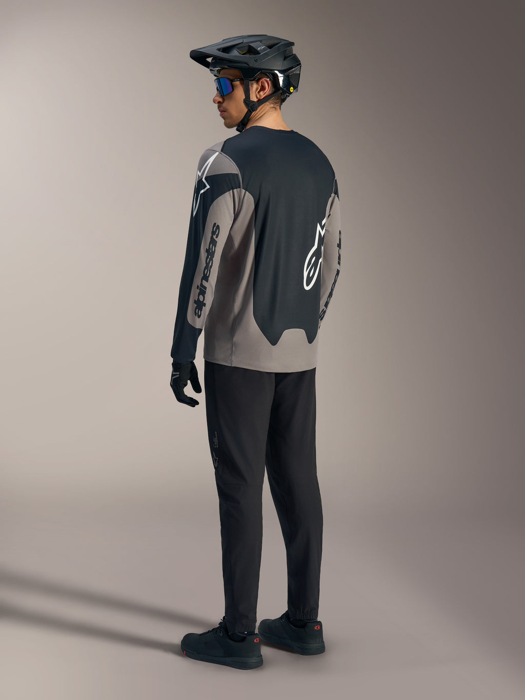 Grijze en zwarte A-Dura Race Jersey met lange mouwen en Alpinestars-branding, van achteren gezien in een MTB-kit.