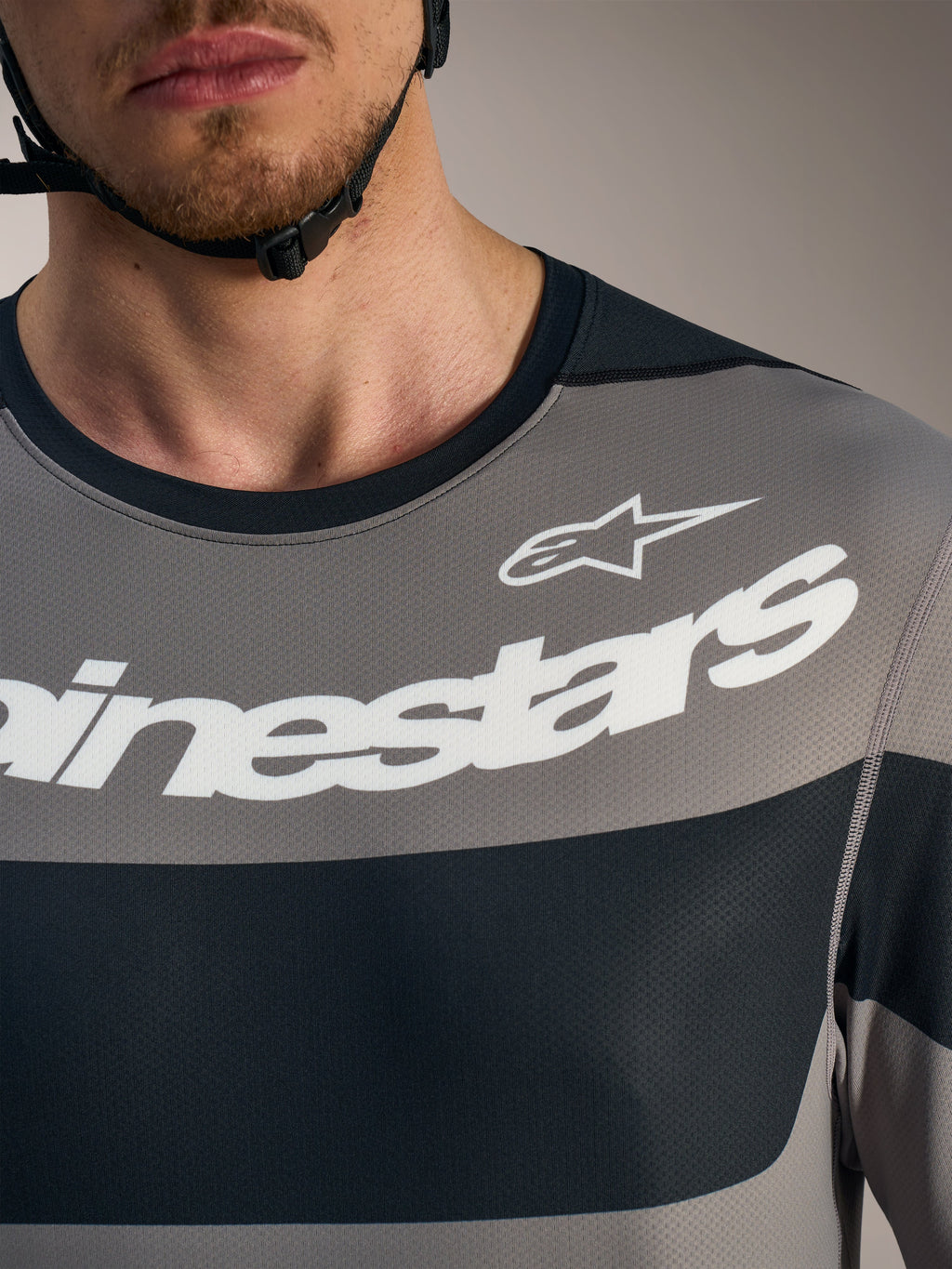 Grijze A-Dura Race trui met lange mouwen, borstdetail met witte Alpinestars-logo's en ademende mesh-stof.
