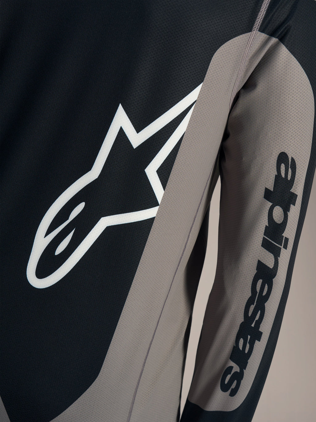 Grijze A-Dura Race jersey detail met wit Astars borstlogo en Alpinestars woordmerk op de mouw.